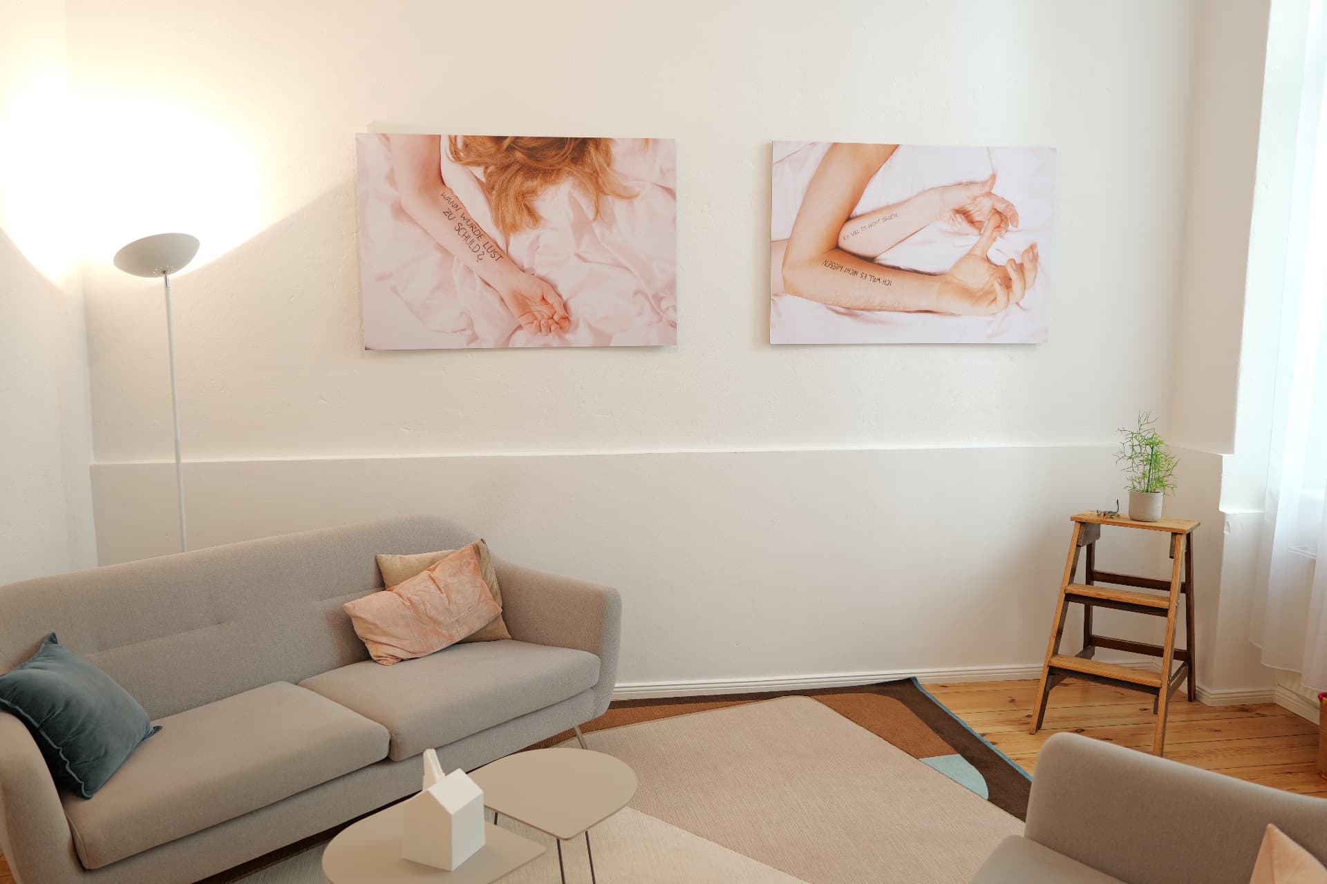 Heller Therapieraum mit Sofa, Kissen und Kunstwerken an der Wand