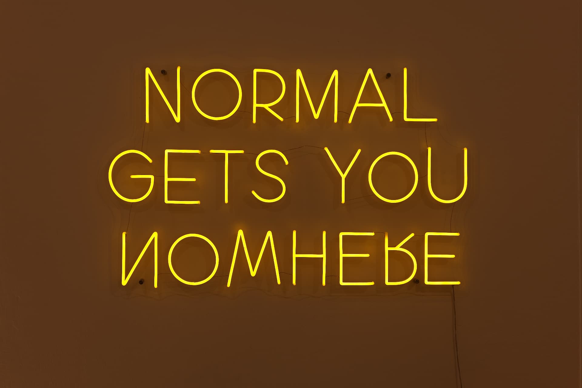 Neonschriftzug „Normal gets you nowhere“ an der Praxiswand